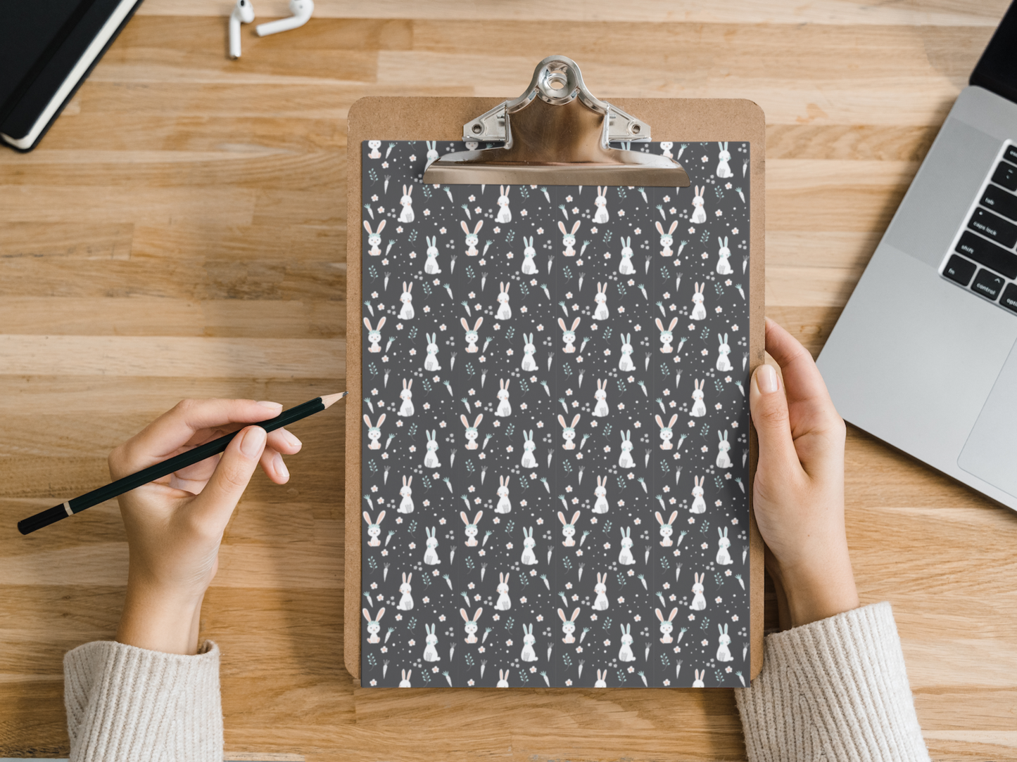 The dollhouse wallpaper pattern of cute bunnies is held by a woman above a desk