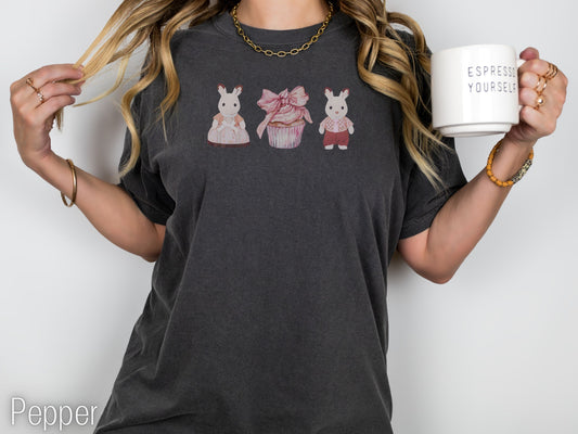 Person wearing a dark gray t-shirt with cartoon character designs, holding a mug.