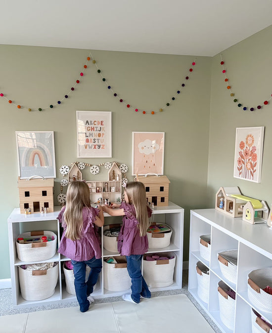 Twin girls are playing in an organized playroom.