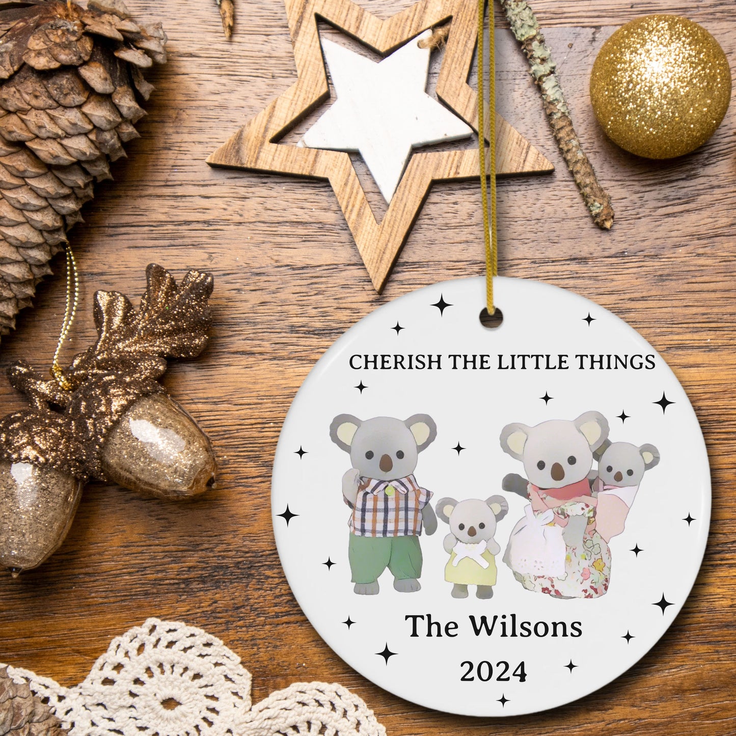 Decorative Christmas ornament with calico critters family on a wooden surface with festive decorations.