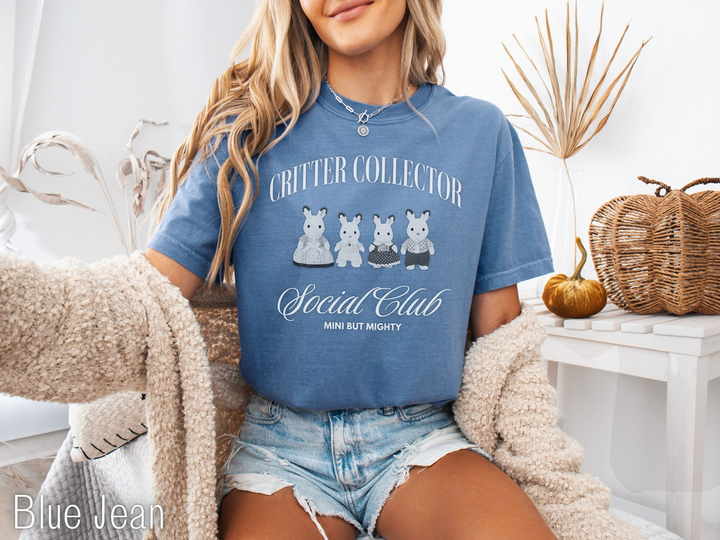 Person wearing a blue t-shirt with 'Critter Collector Social Club' text and graphics, sitting in a cozy room.