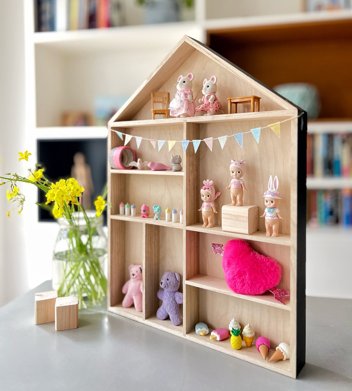 A wooden display shelf displaying cute items, with a paper bunting in pastel colors decorating it