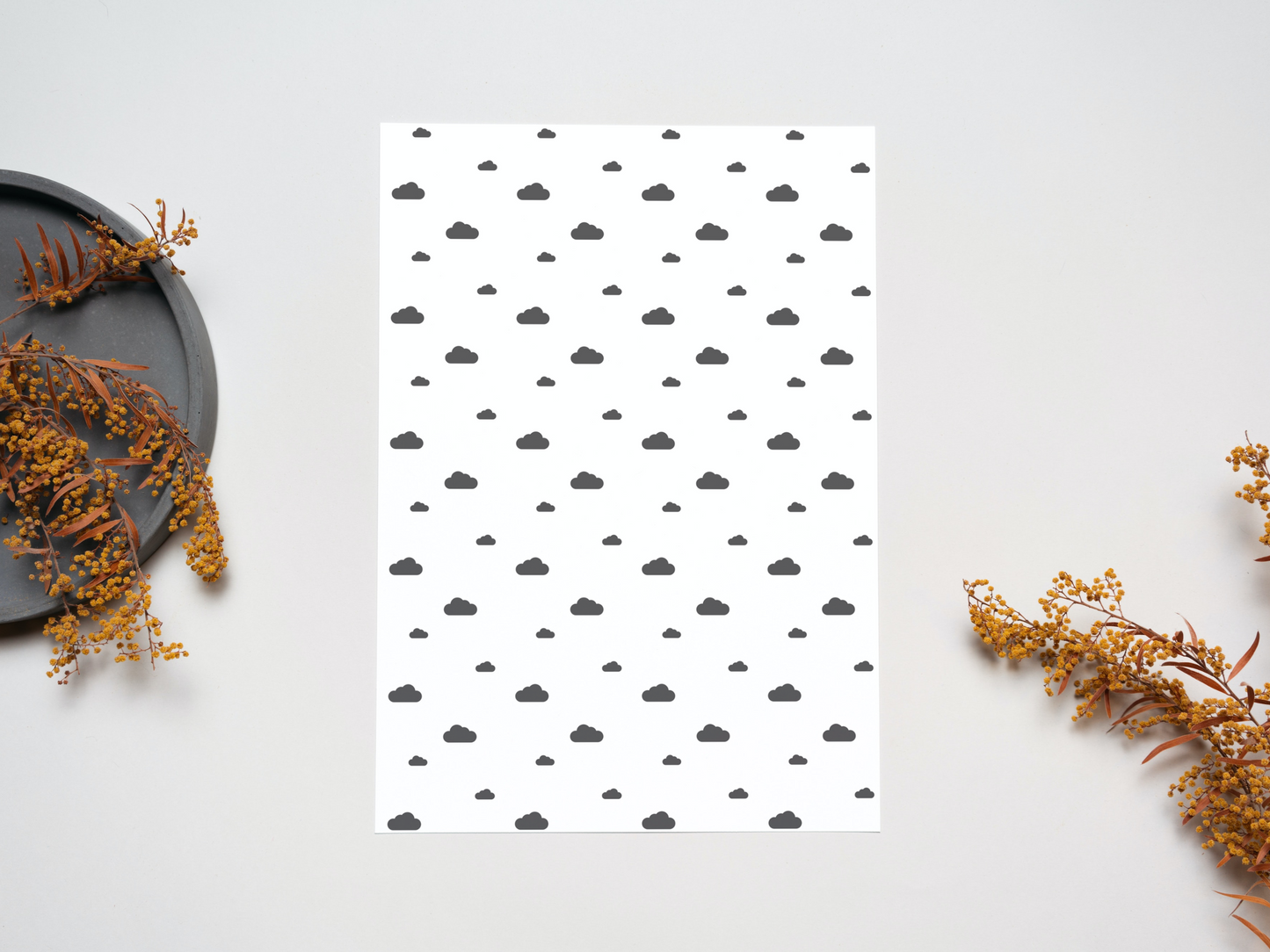 The dollhouse wallpaper pattern of Nordic style little black clouds is set on a table near some dry leaves