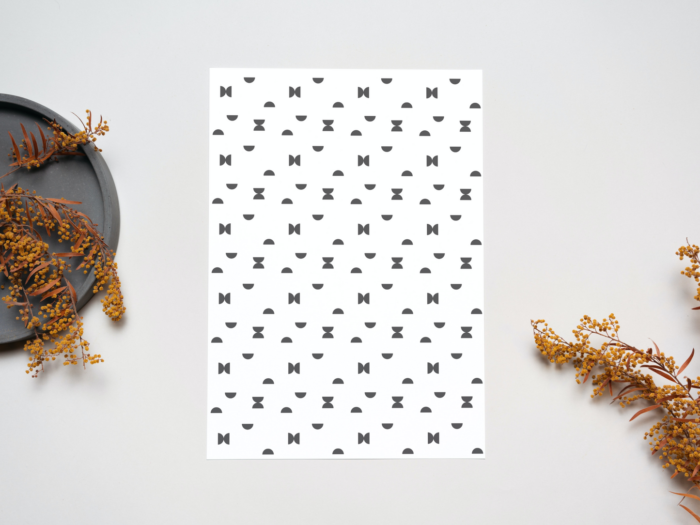The Nordic black semi circles dollhouse wallpaper on a table near dry leaves