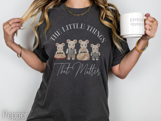 Person wearing a dark gray t-shirt with a graphic and text, holding a mug.