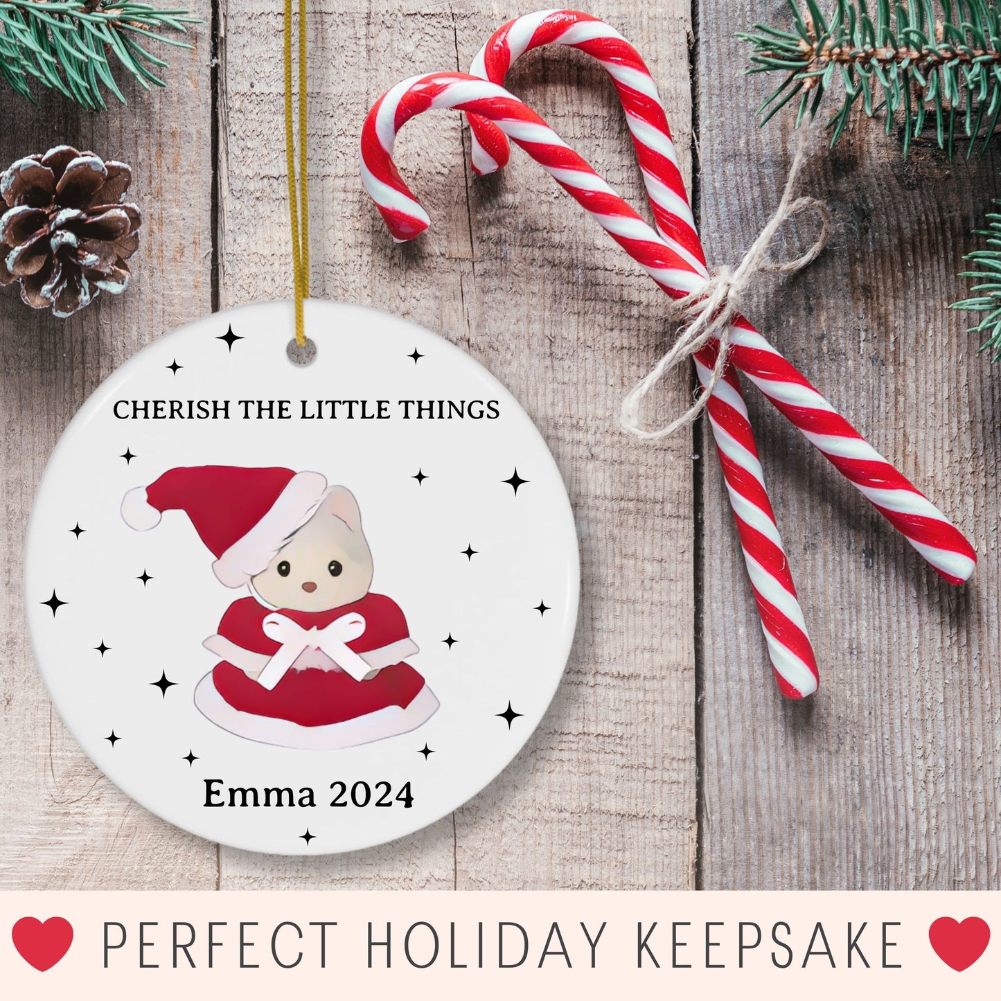 Personalized Christmas ornament with a calico critter in a Santa hat, candy canes, and pine cones on a wooden background.