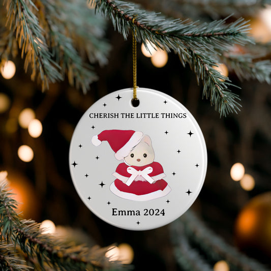 Christmas ornament with a cute illustration of a baby bear in a Santa outfit, hanging on a tree branch.