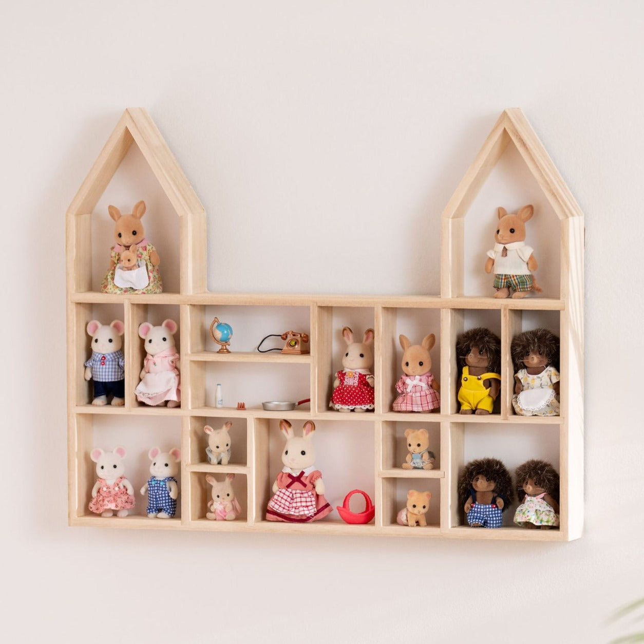 A castle-shaped wooden toy display shelf with Calico Critters display hung on the wall
