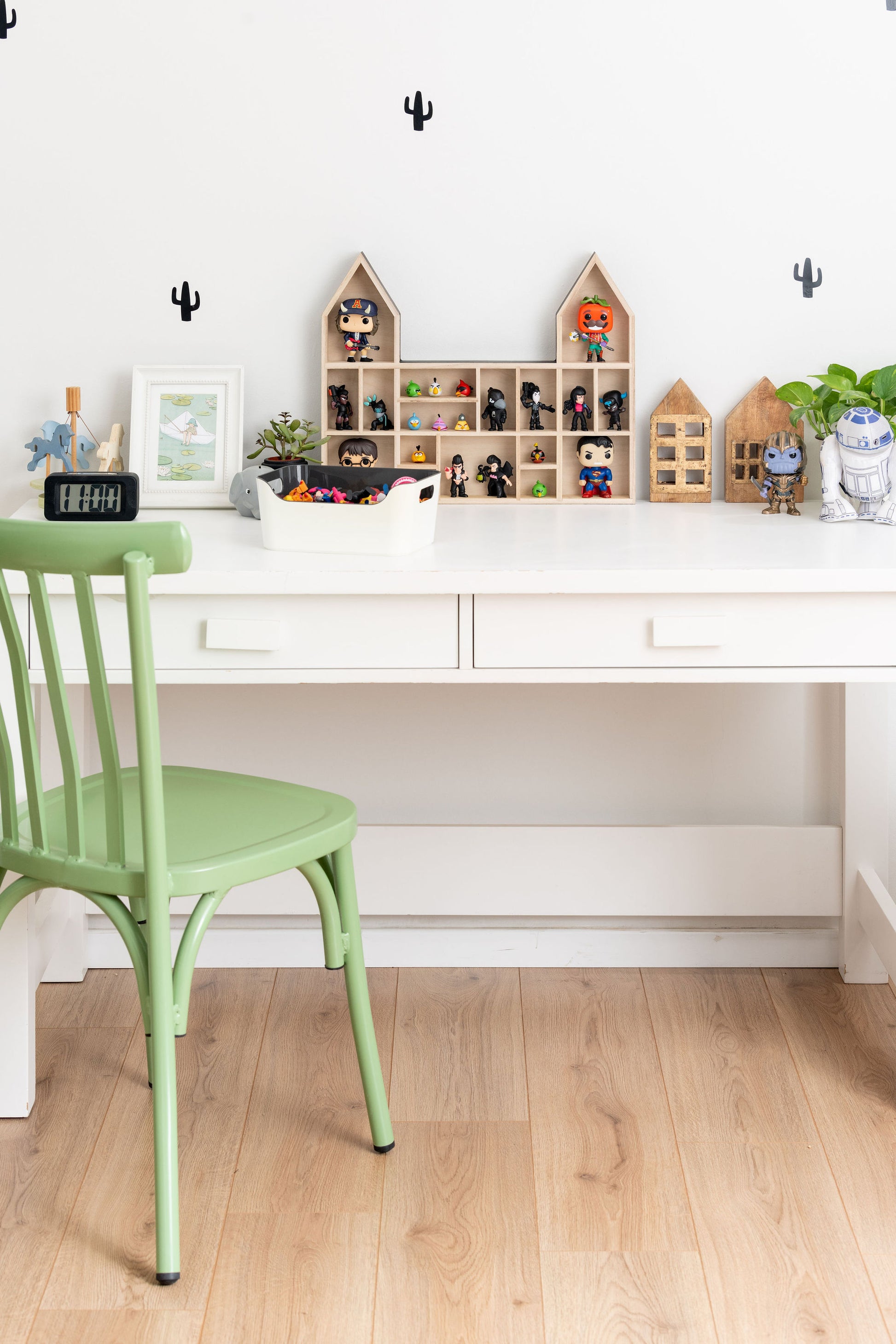A boy's desk and chair with a castle-shaped wooden toy display shelf standing on it with POP figures and angry birds 