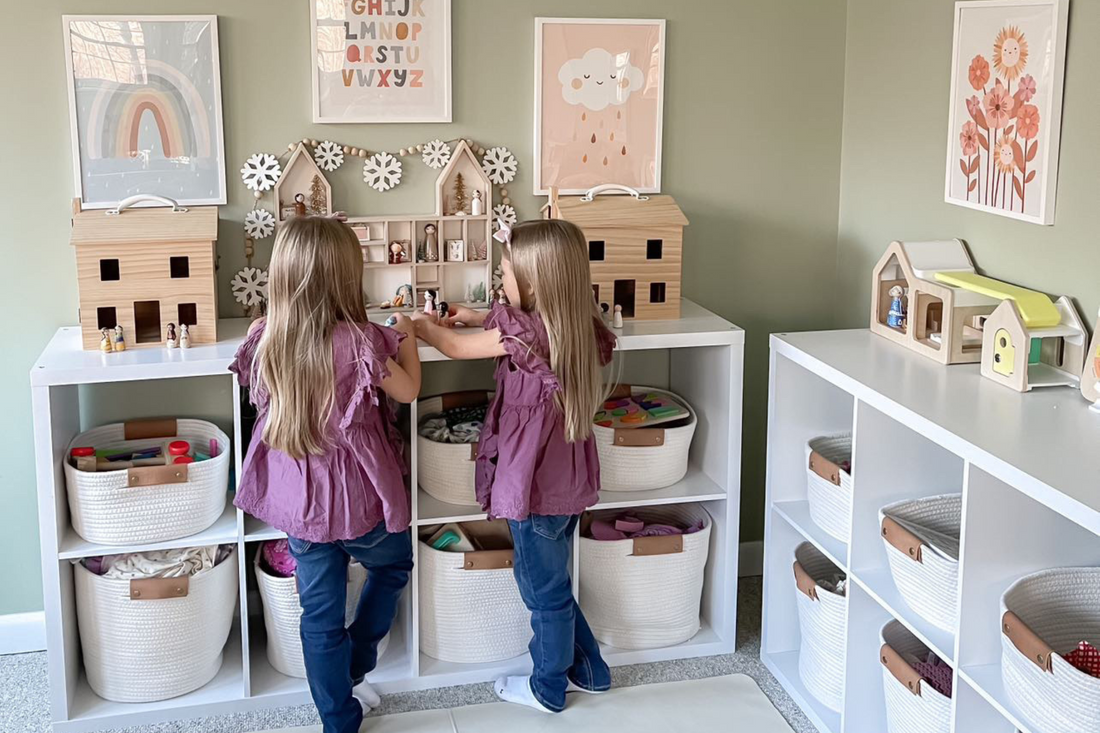 Twin girls playing in a playroom with open shelving.