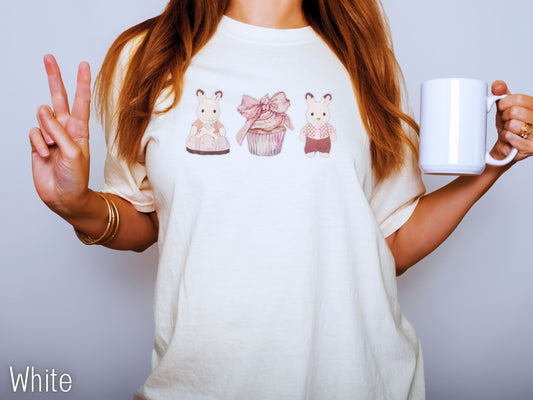 Person wearing a white t-shirt with cartoon designs and holding a white mug.