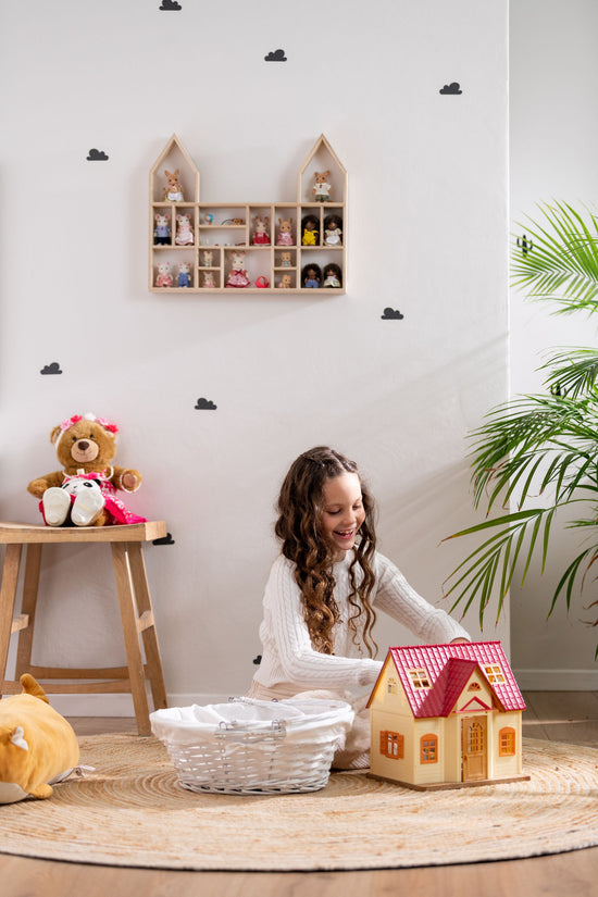 Smiley girl playing with Calico Critters near a castle-shaped wooden toy display shelf that is hung on the wall