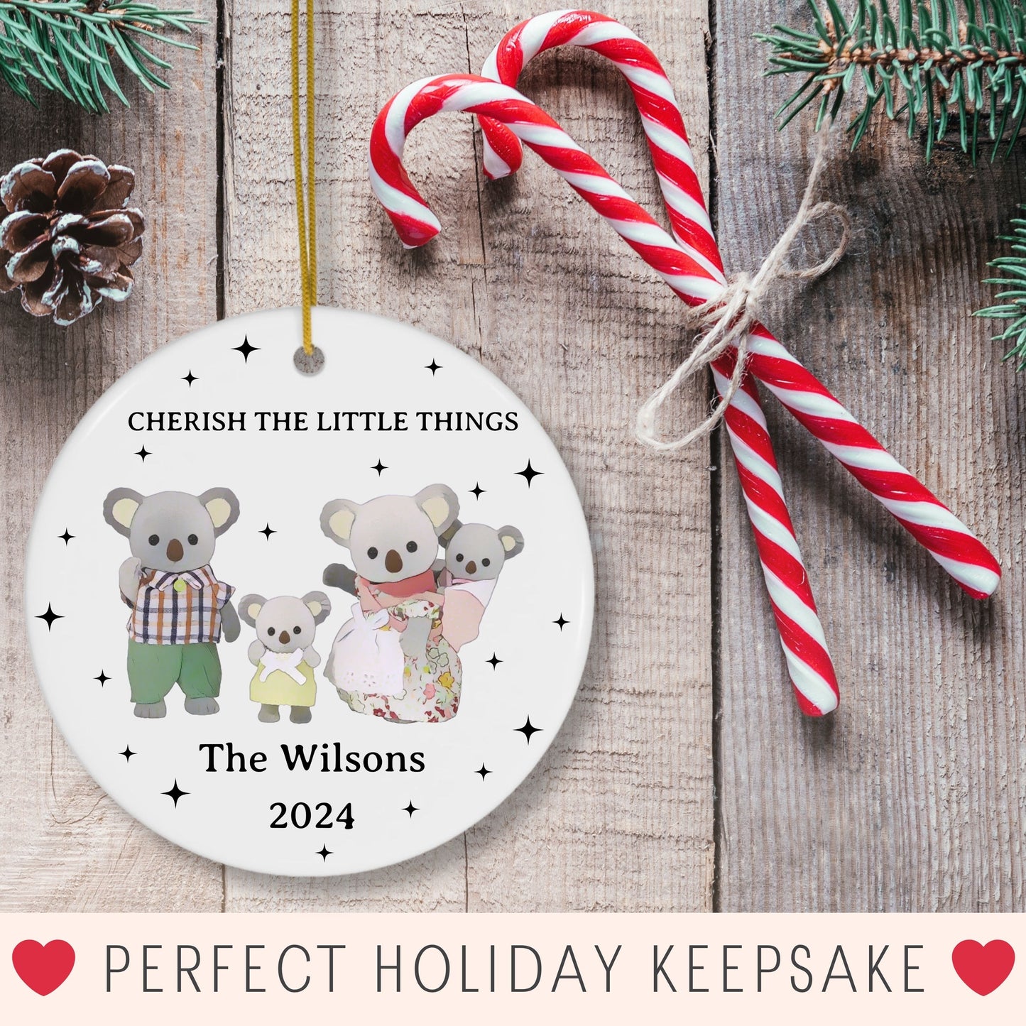 Personalized Christmas ornament with koala family design on a wooden surface with candy canes and pine cones.