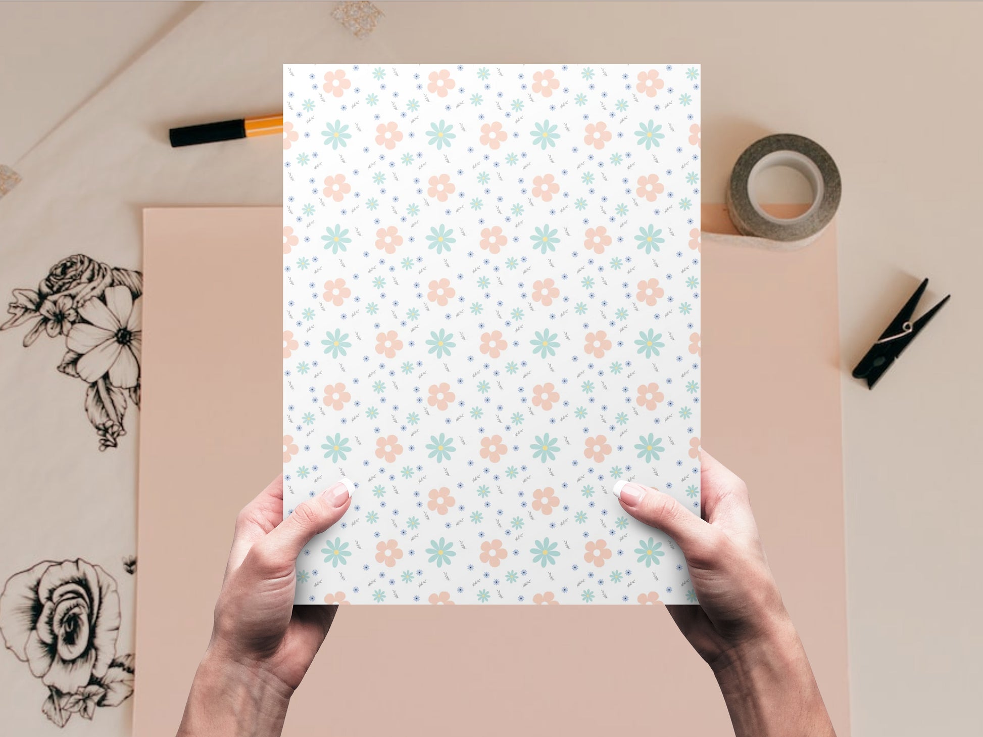 The dollhouse wallpaper pattern of flowers in pastel colors is held by a woman above a desk