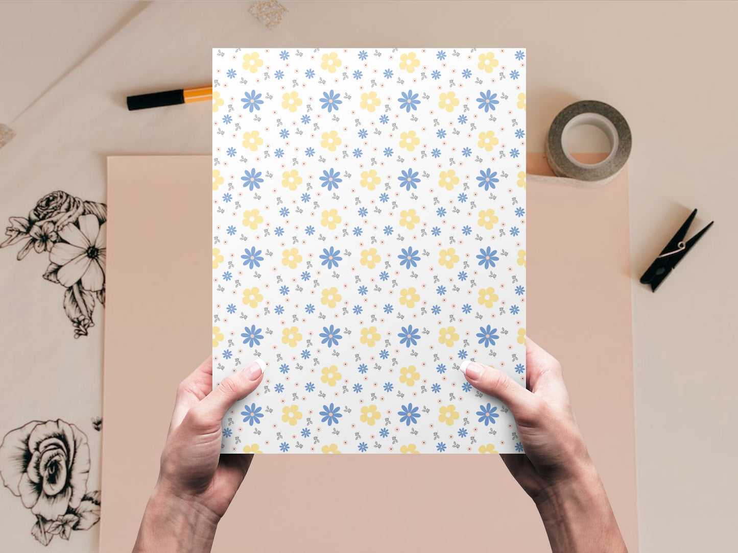 The dollhouse wallpaper pattern of blue and yellow flowers is held by a woman above a desk