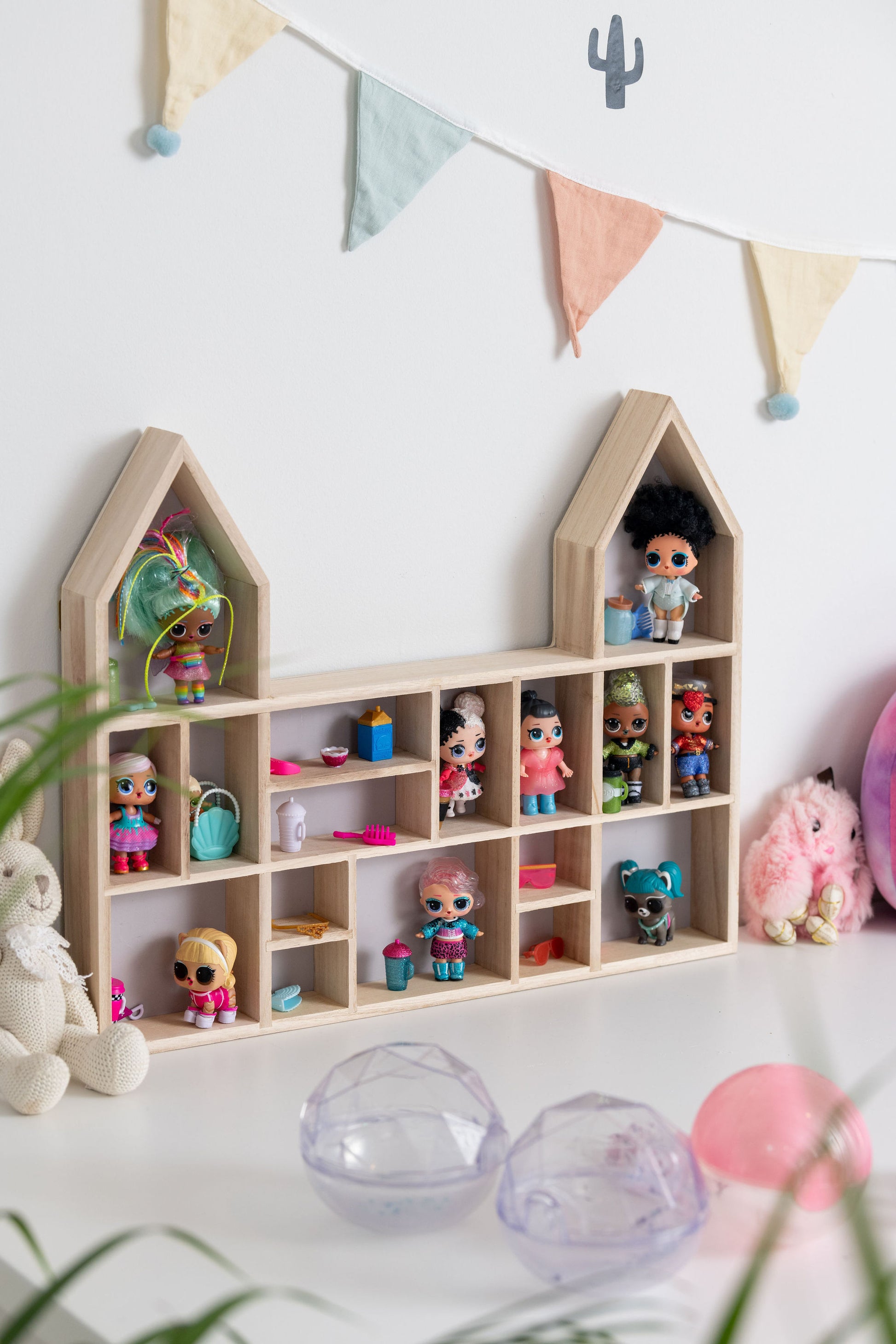 LOL dolls in a castle-shaped wooden toy display shelf with a gray-colored backboard (side view)