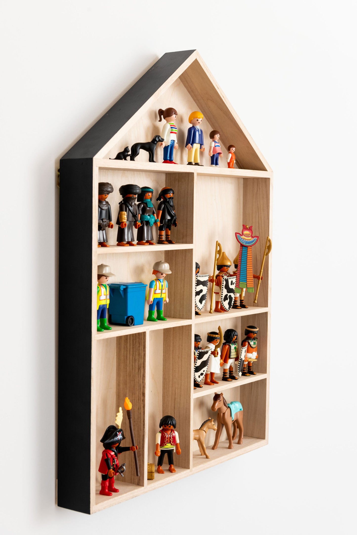 Side view closeup on a house shaped shelf with Playmobil figures.