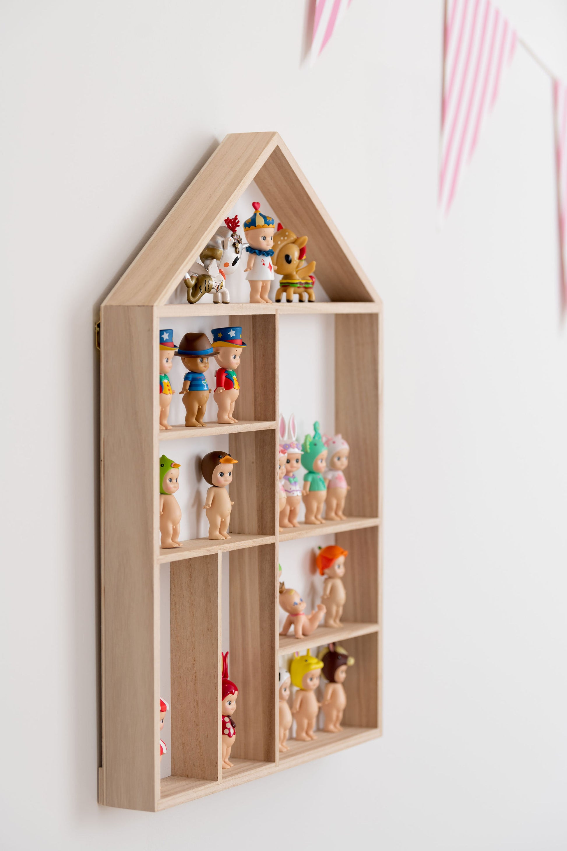 Side view closeup on a house-shaped wooden toy display shelf with Sonny Angels