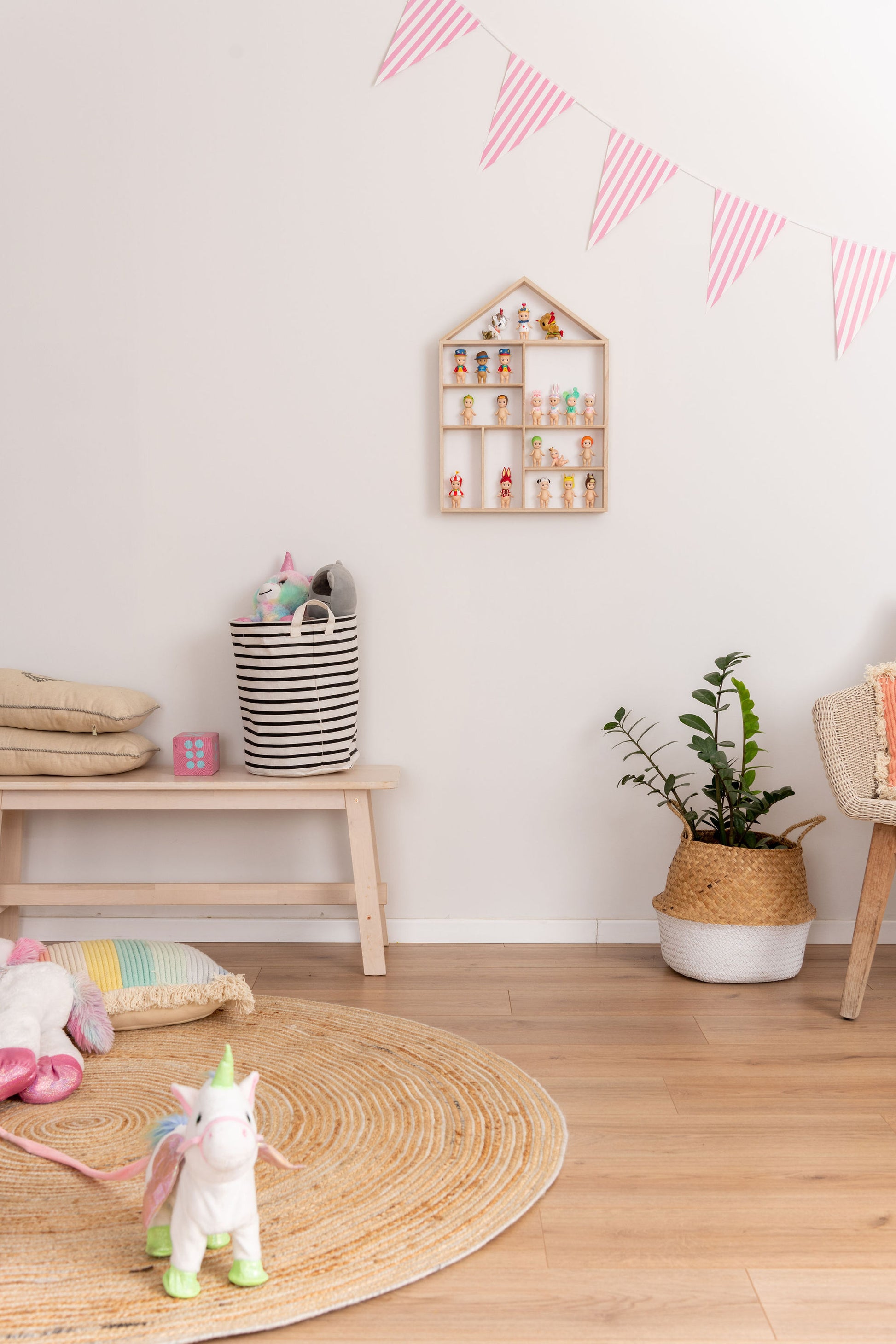 A house-shaped wooden toy display shelf with Sonny Angels hung on the wall in a girl's room